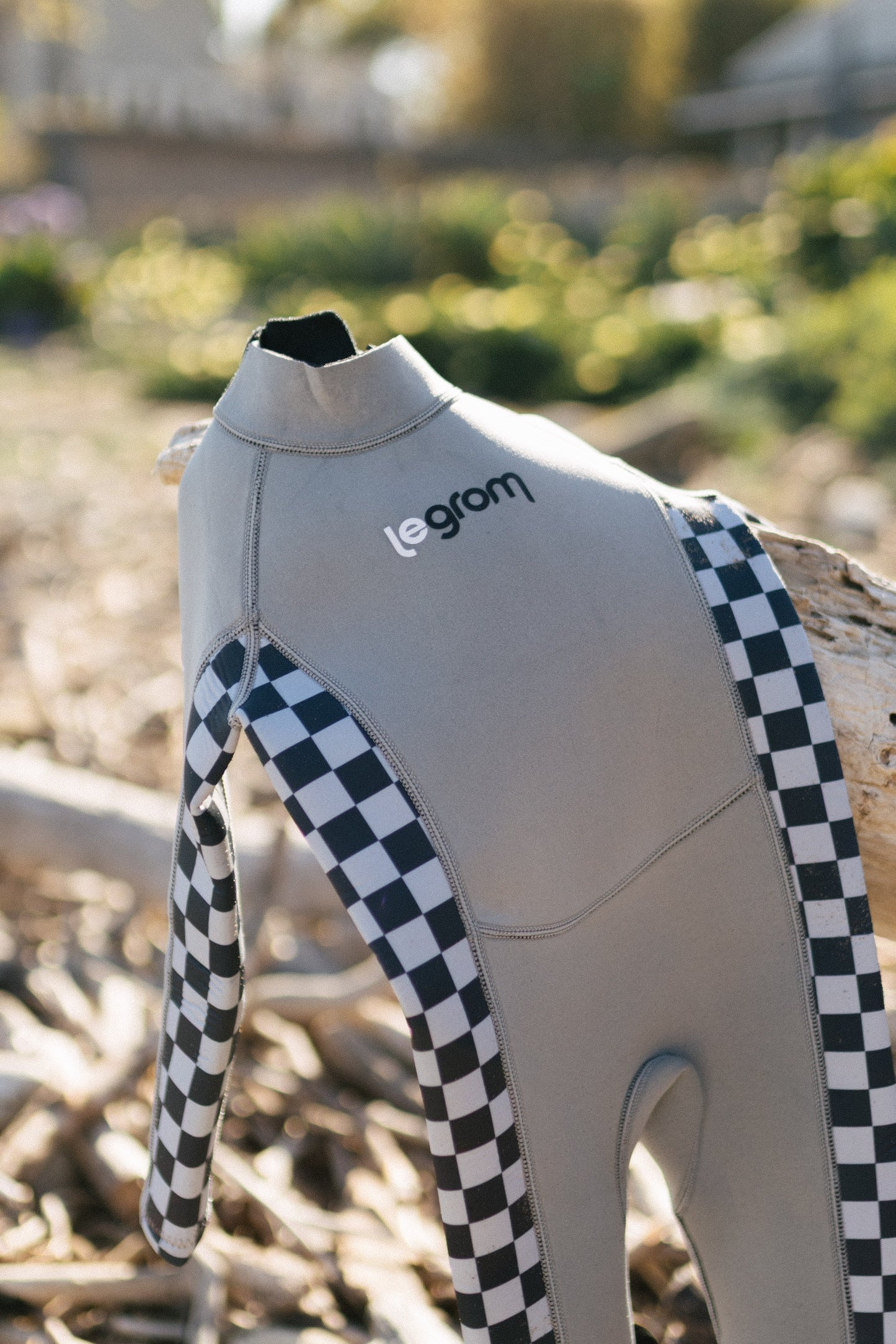 Toddler wearing Le Grom Ash wetsuit walking on the beach, back view